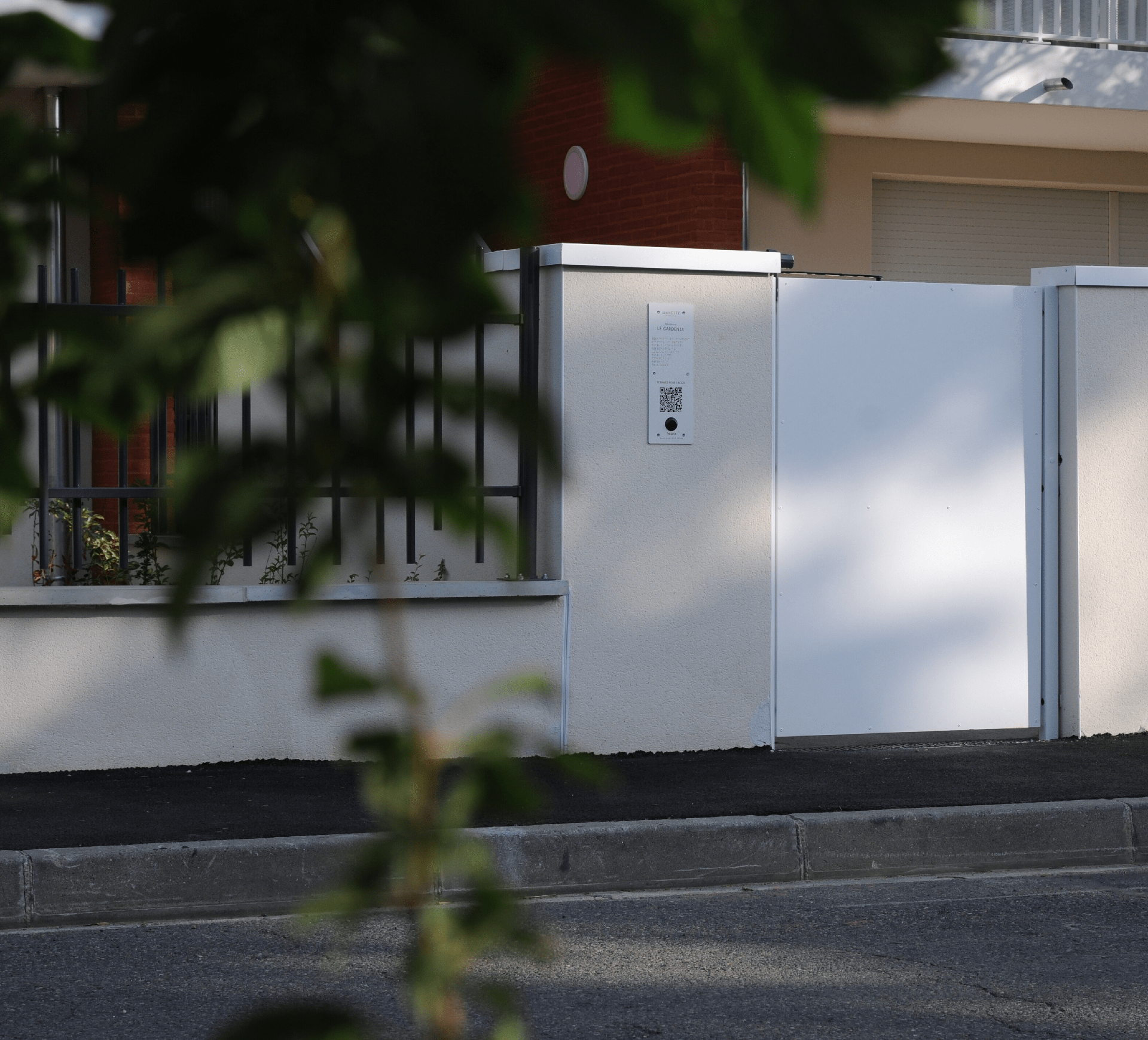 Photographie d'une plaque hapiix installée au niveau d'un portillon à l'entrée d'une résidence.