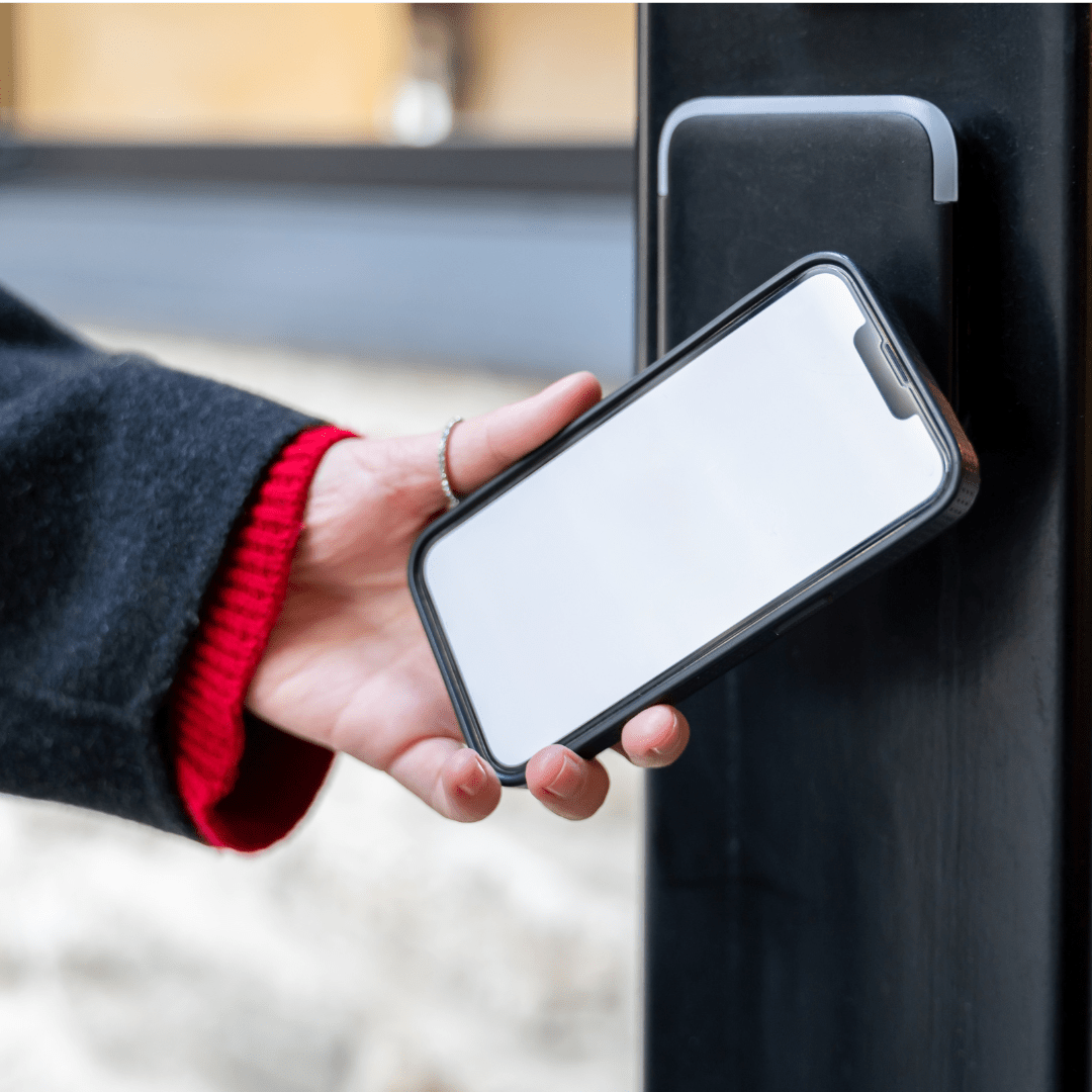 personne qui passe son téléphone devant un lecteur NFC pour ouvrir sa porte.