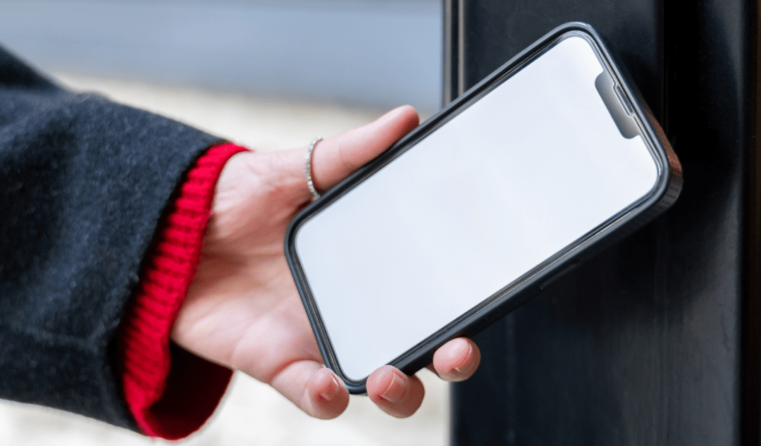 personne qui passe son téléphone devant un lecteur NFC pour ouvrir sa porte.