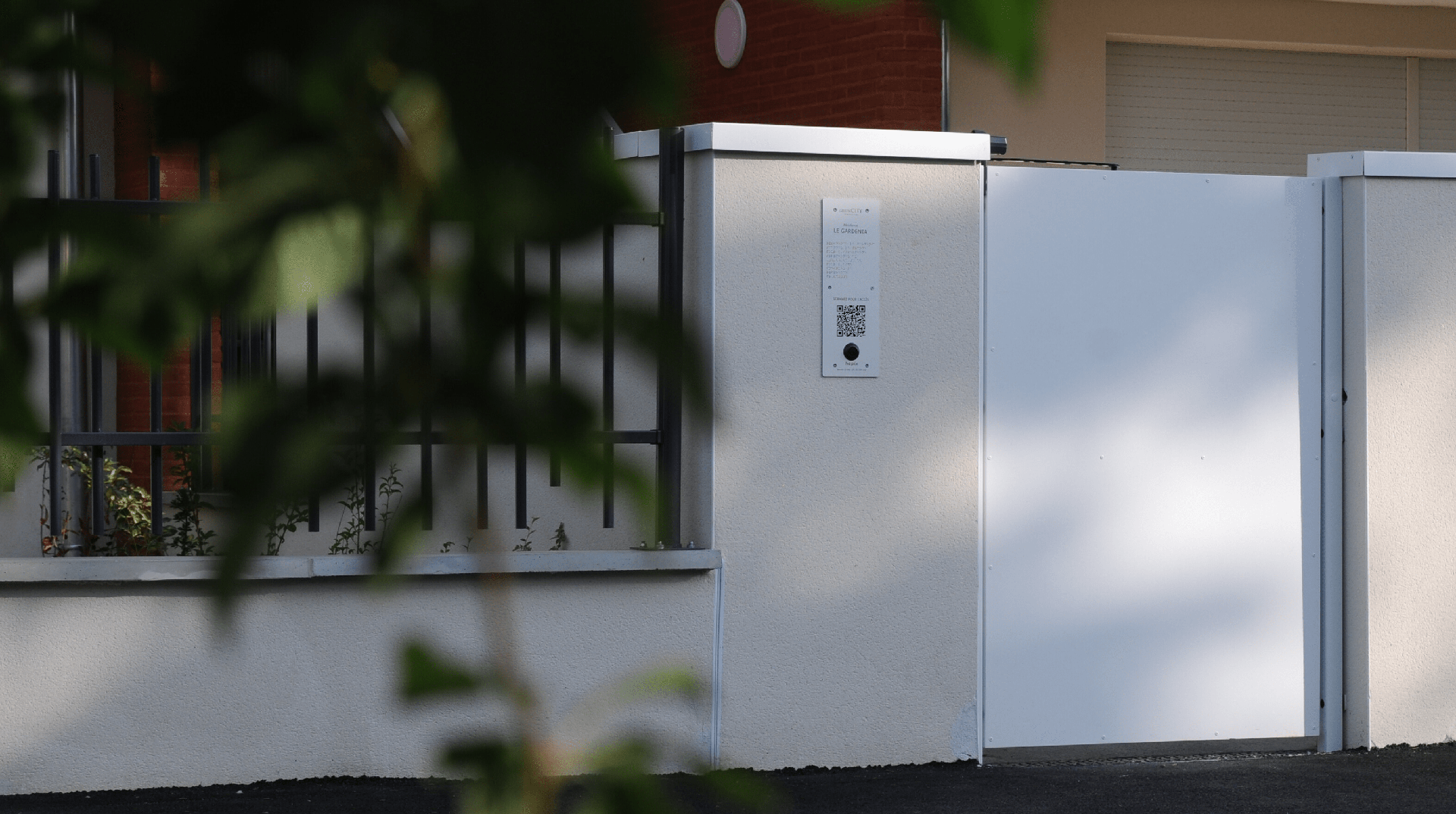 Photographie d'une plaque hapiix installée au niveau d'un portillon à l'entrée d'une résidence.