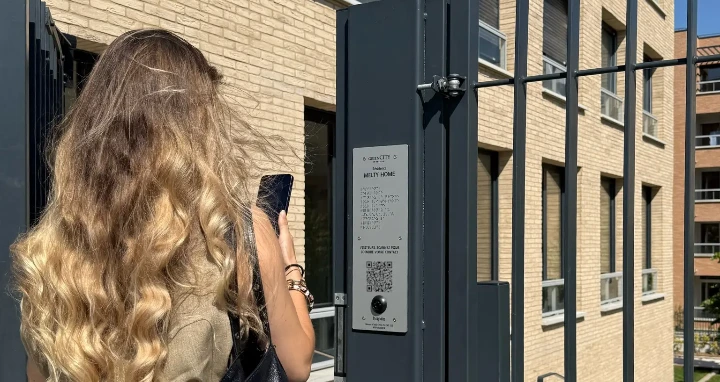 Photo d'une résidente qui accède à son logement en ouvrant le portillon de son bâtiment avec hapiix.